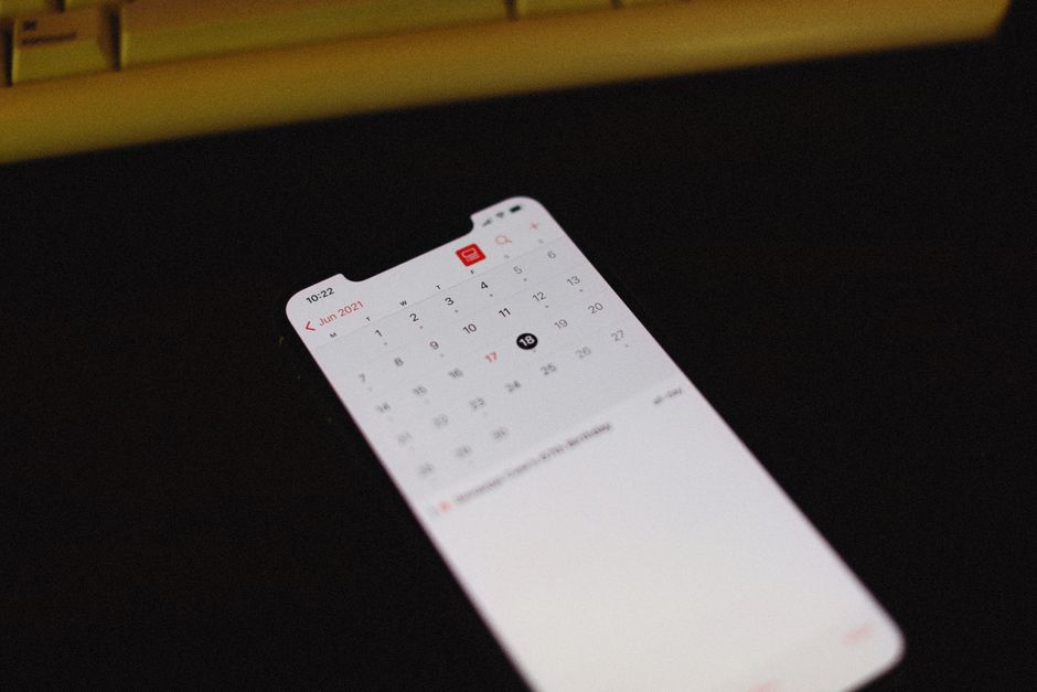 Smartphone com tela do aplicativo de calendário iluminada em um fundo escuro, junho de 2021 visível.