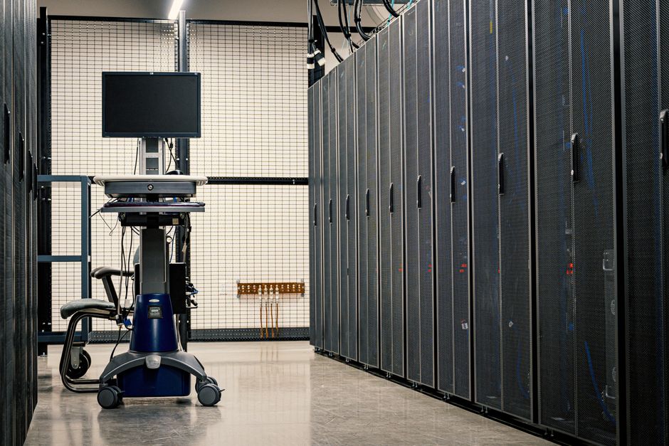 Interior de centro de dados exibindo racks de servidores e equipamentos de operação.