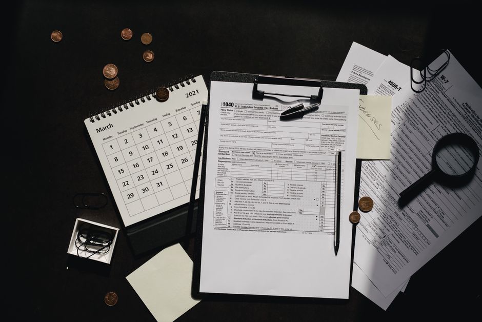 Um espaço de trabalho bem organizado com formulários fiscais, calendário, lupa e suprimentos de escritório para uma preparação de impostos eficiente.