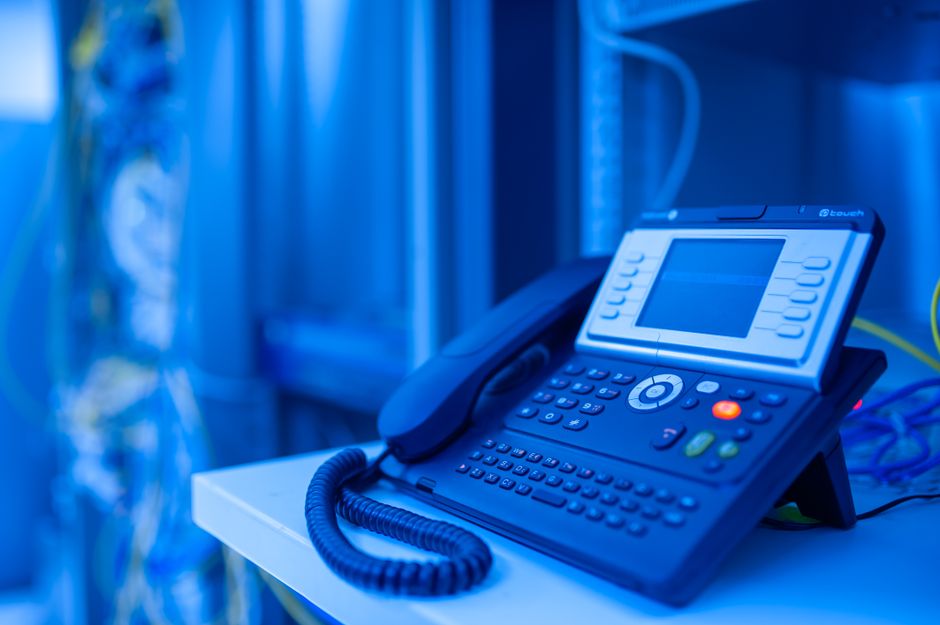Close-up de um telefone de escritório moderno em iluminação azul. Ideal para temas de tecnologia e negócios.